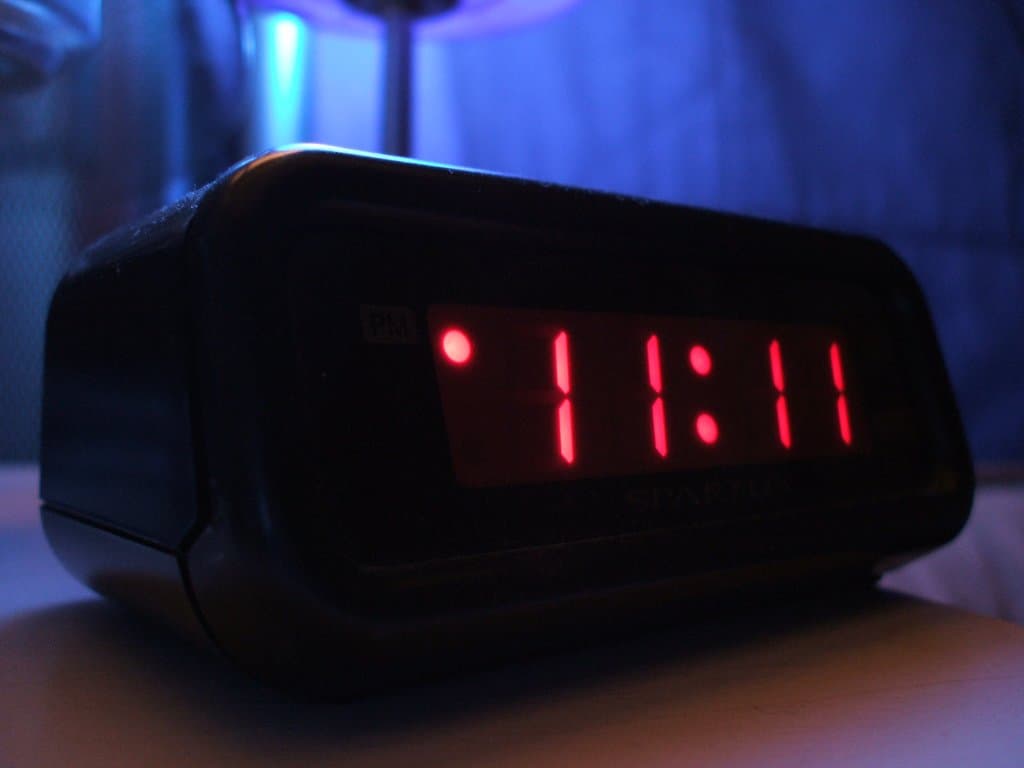 Digital alarm clock displaying 11:11 in the dark, representing 11:11 meaning, synchronicity, and a reality-shifting portal
