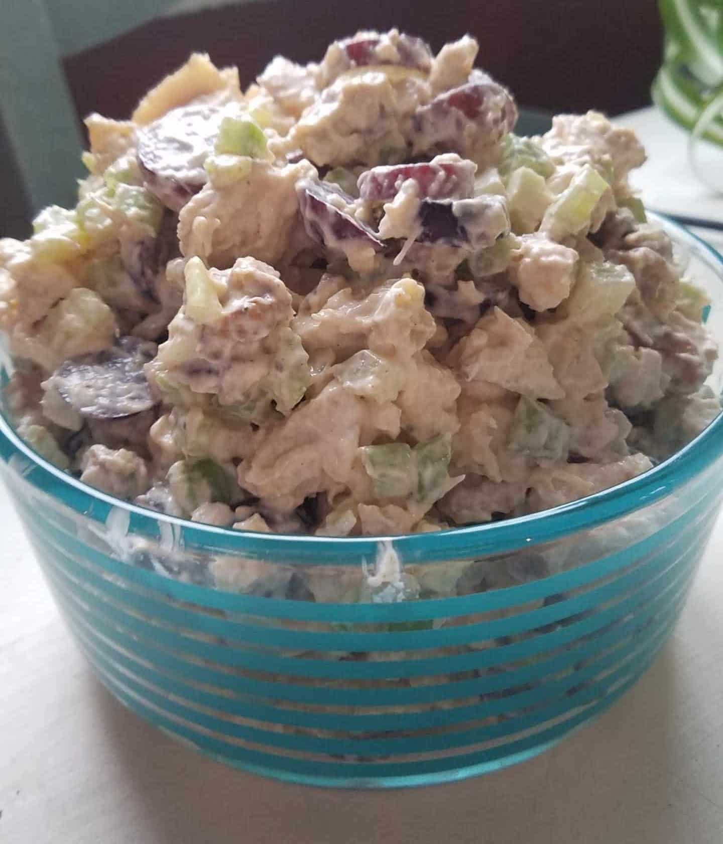 Homemade chicken salad with grapes, walnuts, and celery in a glass bowl