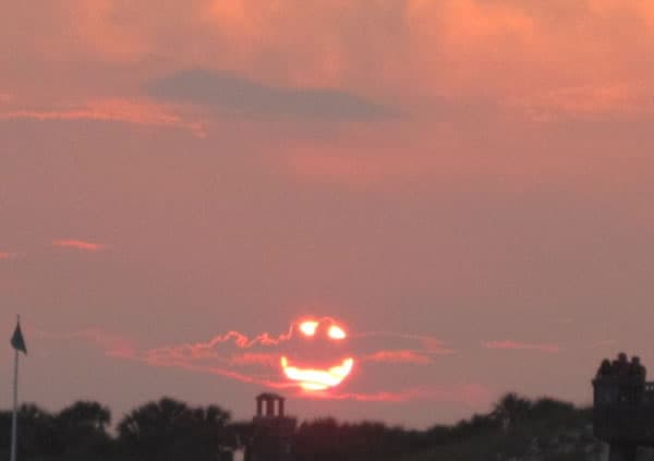 Willingness, oneness, and synchronicity symbolized by a radiant smiling sunset over the horizon