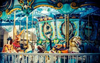 Colorful vintage carousel horses under soft light, symbolizing cycles of vanity, ego, and karma.