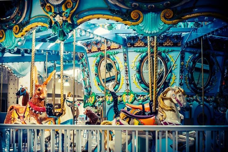 Colorful vintage carousel horses under soft light, symbolizing cycles of vanity, ego, and karma.