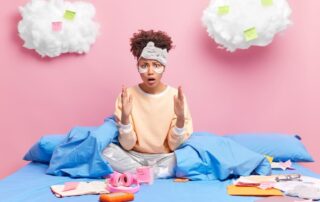 Person sitting on a bed surrounded by scattered thoughts, symbolizing fear, overthinking, and the difference between being scared and being worried