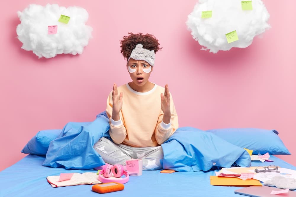 Person sitting on a bed surrounded by scattered thoughts, symbolizing fear, overthinking, and the difference between being scared and being worried