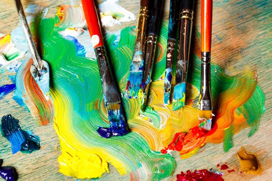 Paintbrushes resting in vibrant paint, symbolizing creative life energy, self-expression, and renewal