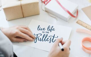 Hands surrounded by gist writing the words “live life to the fullest,” symbolizing gratitude, purpose, and embracing life as a gift