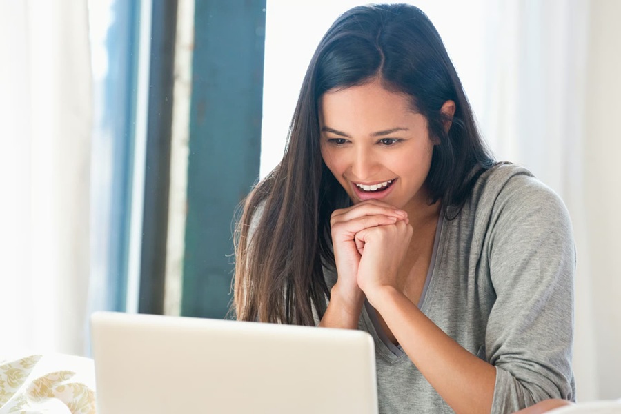 Woman smiling at her laptop after receiving her free psychic email reading from Whispy.com.