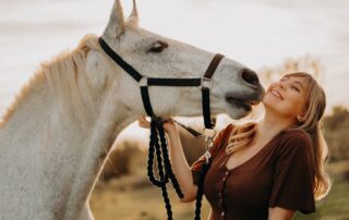 Woman gently connecting with a white horse during wild horse empowerment therapy