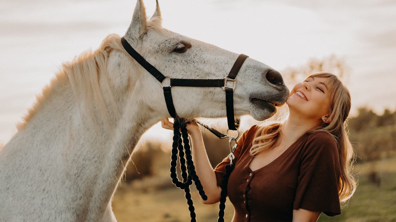 Woman gently connecting with a white horse during wild horse empowerment therapy