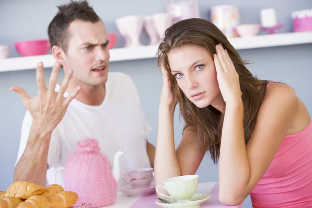 Woman sitting at a table listening to her partner during a serious breakup conversation.