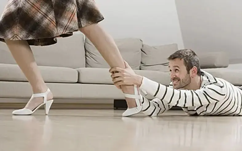 Man clinging to a woman’s leg, symbolizing difficulty letting go in a relationship.