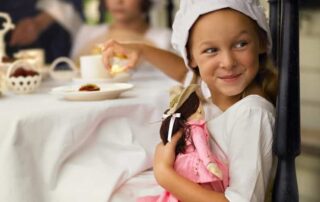 Little girl holding a doll and smiling with quiet confidence, symbolizing self-acceptance and owning who you are