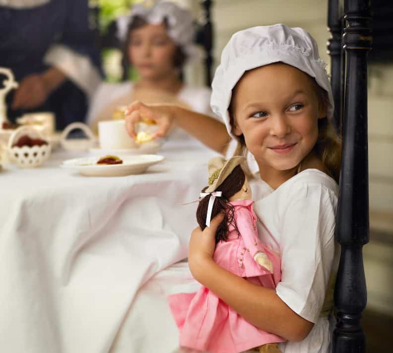 Little girl holding a doll and smiling with quiet confidence, symbolizing self-acceptance and owning who you are
