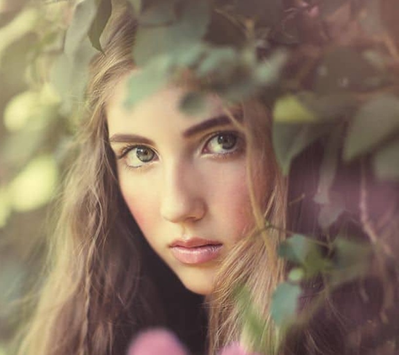 A woman gazing thoughtfully through leaves, symbolizing intuition and inner awareness