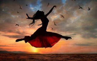 Woman leaping joyfully at sunrise symbolizing freedom, transformation, and living with joy