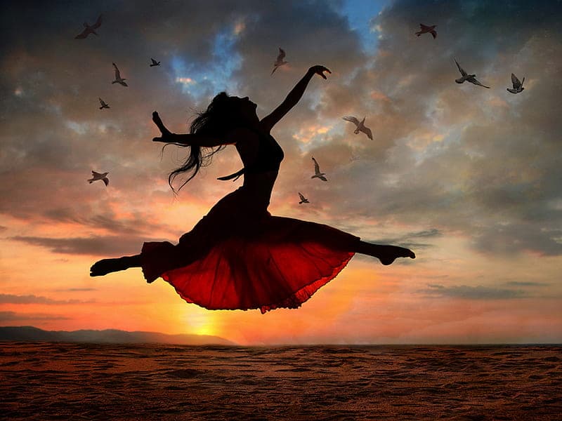 Woman leaping joyfully at sunrise symbolizing freedom, transformation, and living with joy
