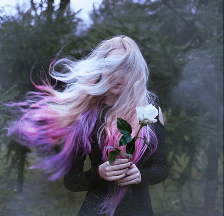 Person holding a white rose with flowing hair, symbolizing self-awareness, innocence, and releasing assumptions