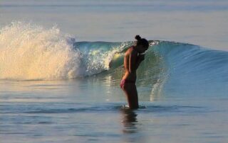 Psychic Lilly standing in still ocean water beneath a soft wave, symbolizing the calm and power of divine love and soul connection before meeting in person.