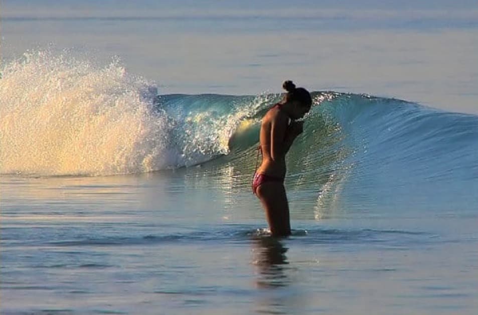 Psychic Lilly standing in still ocean water beneath a soft wave, symbolizing the calm and power of divine love and soul connection before meeting in person.