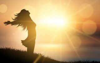 Silhouette of a person standing with open arms in sunlight, symbolizing soul growth and self awareness. Shining her inner light.