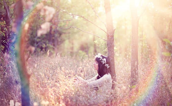 Woman experiencing spiritual awakening in a forest surrounded by light and energy