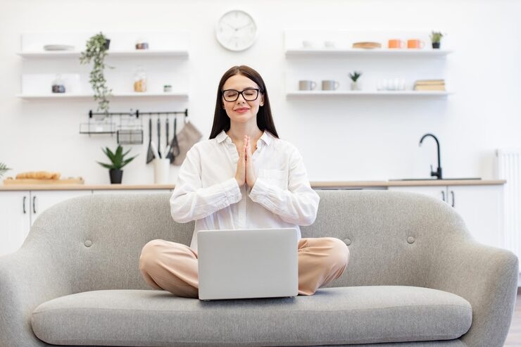 Woman meditating with laptop during online spiritual counseling session
