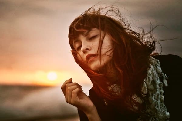 Woman in peaceful reflection at sunset symbolizing spiritual empowerment and awakening to divine consciousness.