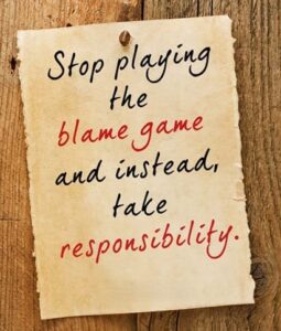 Motivational quote saying stop playing the blame game and take responsibility on aged paper background