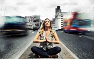 Woman meditating calmly in the middle of a busy city street, symbolizing emotional awareness and spiritual presence amid chaos