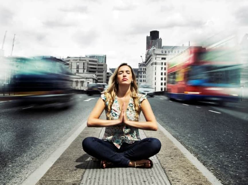 Woman meditating calmly in the middle of a busy city street, symbolizing emotional awareness and spiritual presence amid chaos