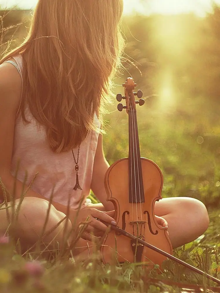 A woman sitting quietly in the light with a violin, symbolizing how spiritual practice reshapes perception and reveals the unity of material and sacred worlds.
