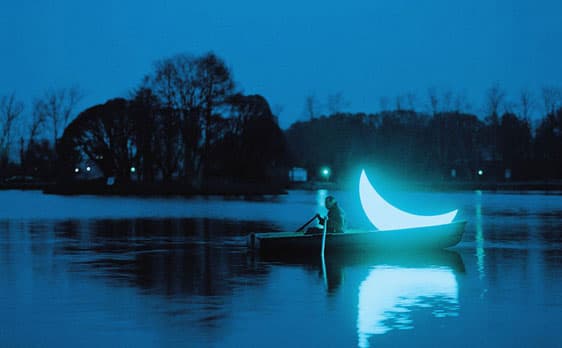 Dreamlike scene of a person rowing a boat with a glowing crescent moon at night